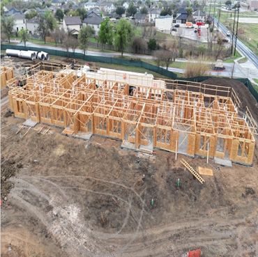 A wooden framework of a building under construction on a muddy site.