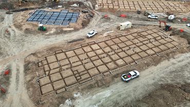 Aerial view of a construction site with foundation work and vehicles.