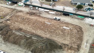 Aerial view of a cleared construction site with scattered materials and a white truck.