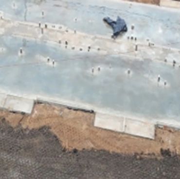 Concrete foundation slab laid out at a construction site beside a road.