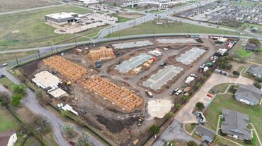 Aerial view of a residential construction site with wooden frames and concrete foundations.