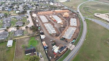 Aerial view of a housing construction site near a curved road.