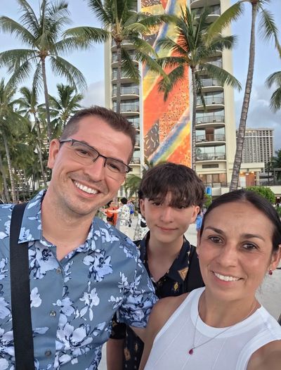 Family selfie on a tropical beach with palm trees.