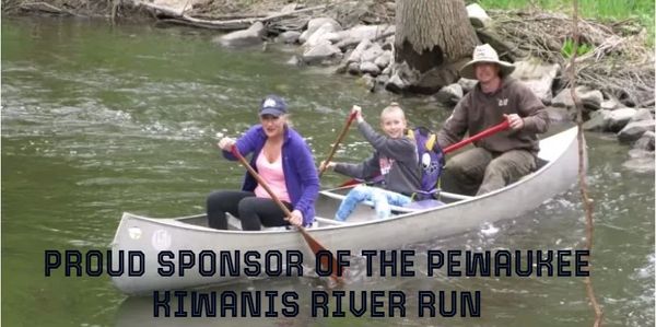 Three people paddling a canoe on a river during the Pewaukee Kiwanis River Run.