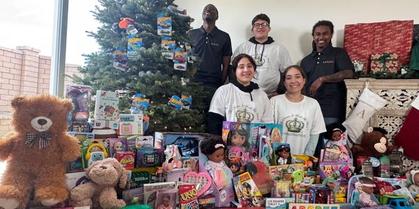 Group photo with toys for donation by Christmas tree.