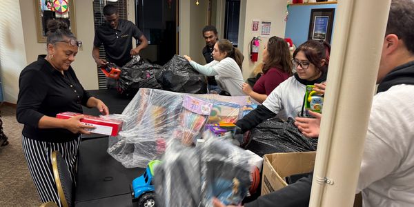 People packing toys into bags at a community event.