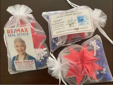 Gift bags with RE/MAX Real Estate business cards and red star decorations.