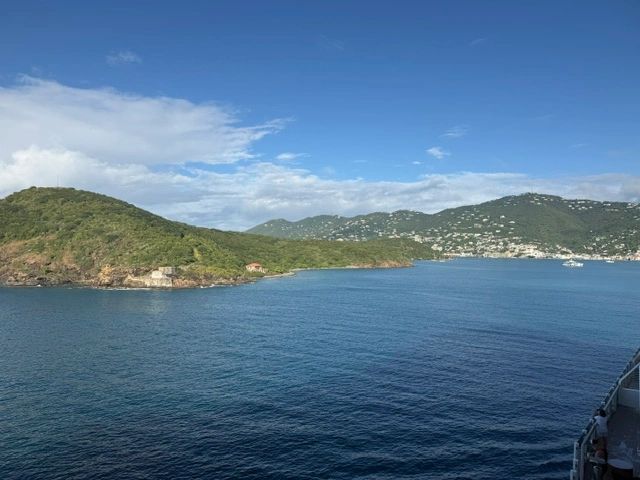 Calm blue ocean with green hills under a clear sky.