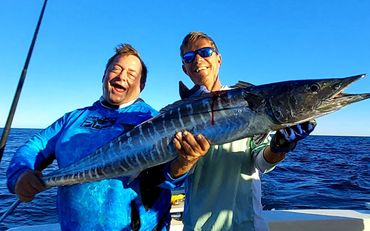 Smiling mans in a boat, fish in hand.