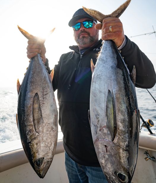 A man looks at two fish lying in front of him