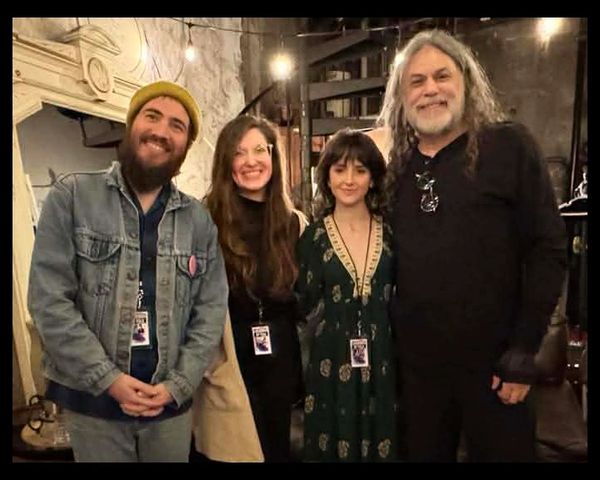 Four people smiling indoors, posing for a photo together.