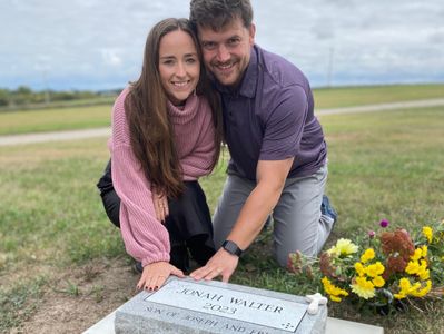 Man and woman kneeling by a tombstone