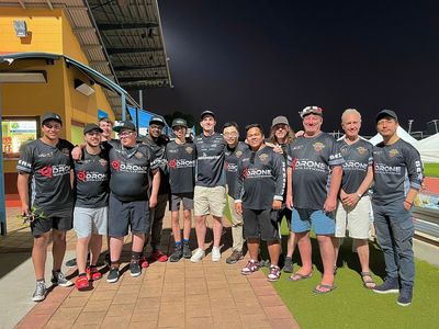 Group photo of drone racing team members in matching shirts at night.