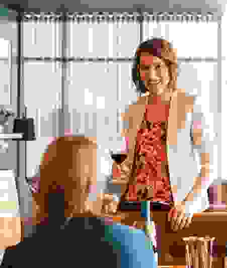 Photo: Fran Marshall. Emma Shaw is smiling at a person, seated with their back to the camera. She ho