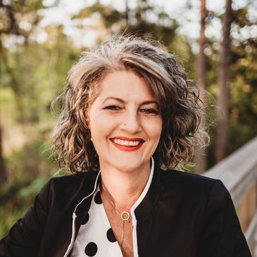 Smiling woman with curly hair outdoors.