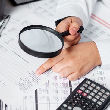 IRS Audit Representation, a male hand holding a magnifying glass over a document