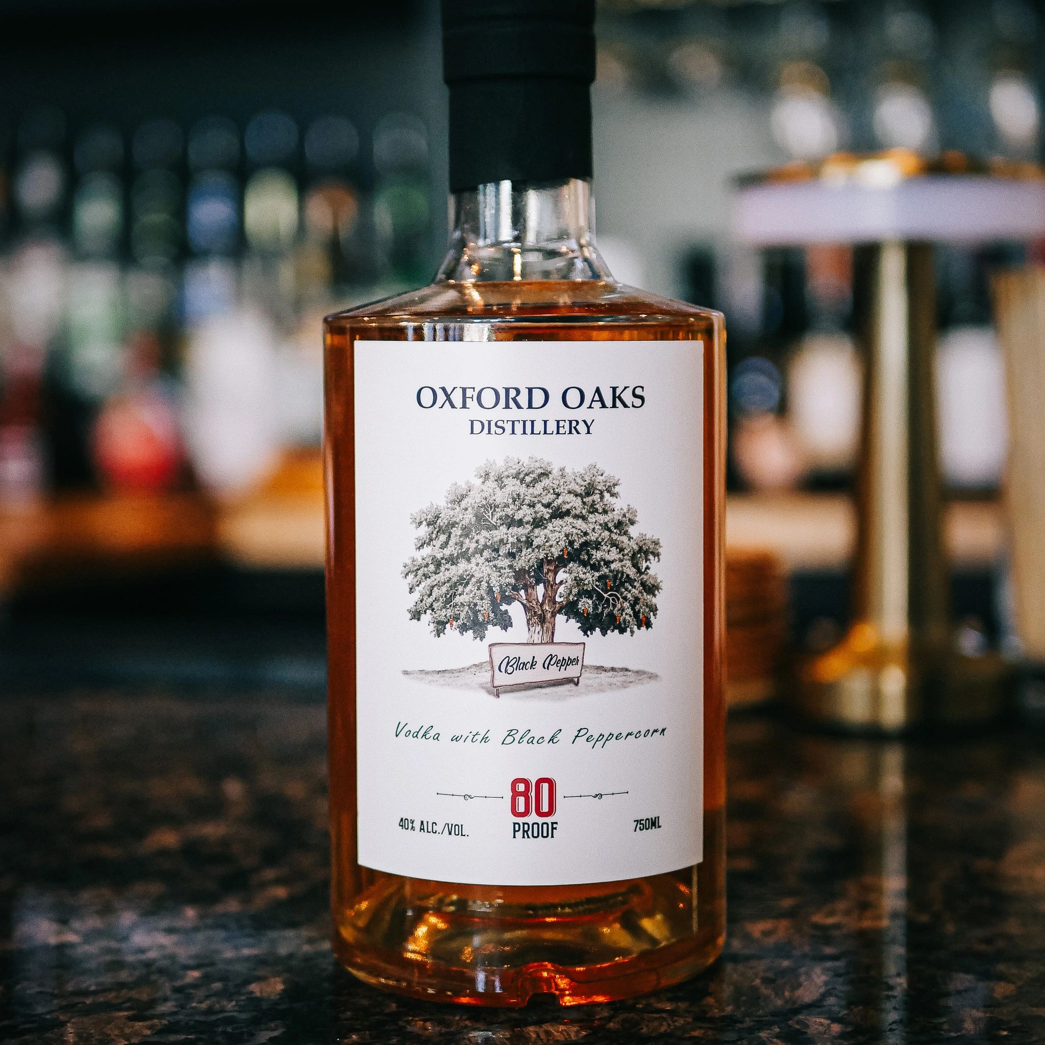 A bottle of Oxford Oaks Distillery vodka infused with black peppercorns displayed on a countertop.
