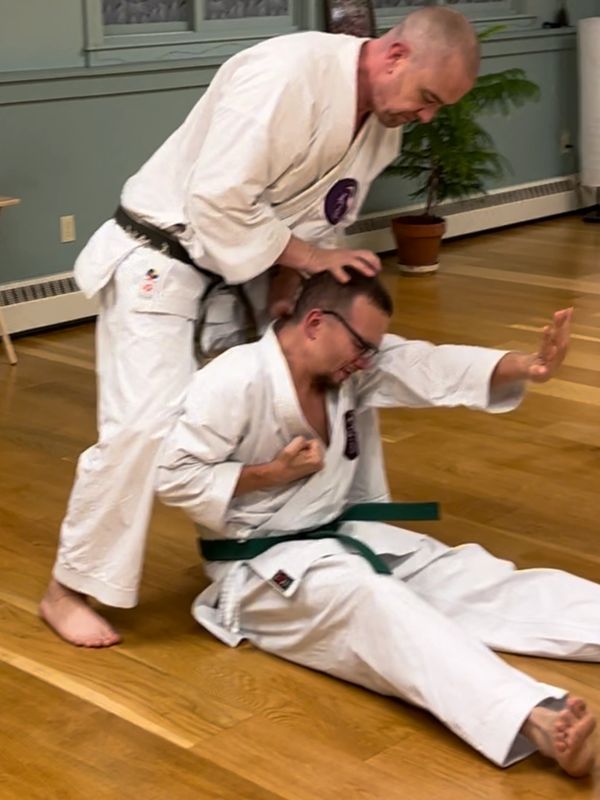 Two men practicing martial arts with one on the ground.