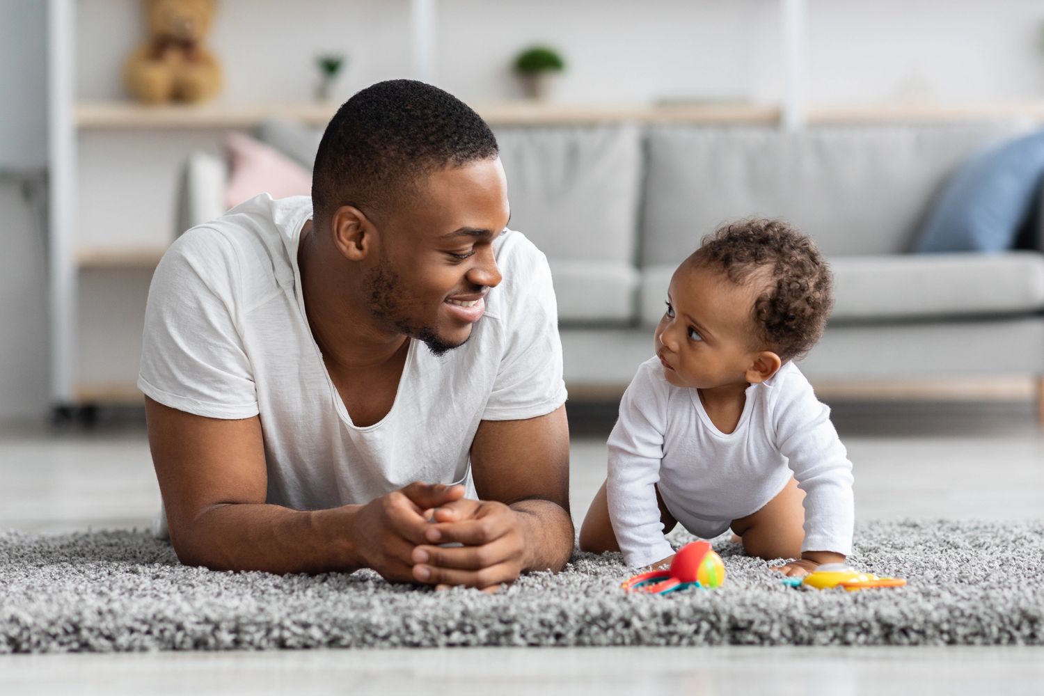 Man and baby lying on the floor looking at each other.