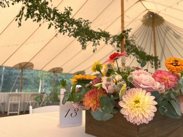 Bouquet on table in the tent, decorated with greenery.