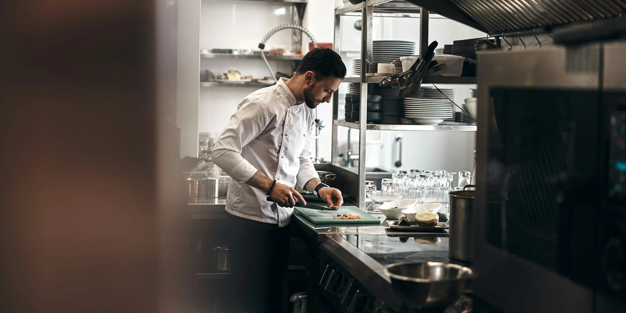 Chef carefully chopping ingredients in a professional kitchen.