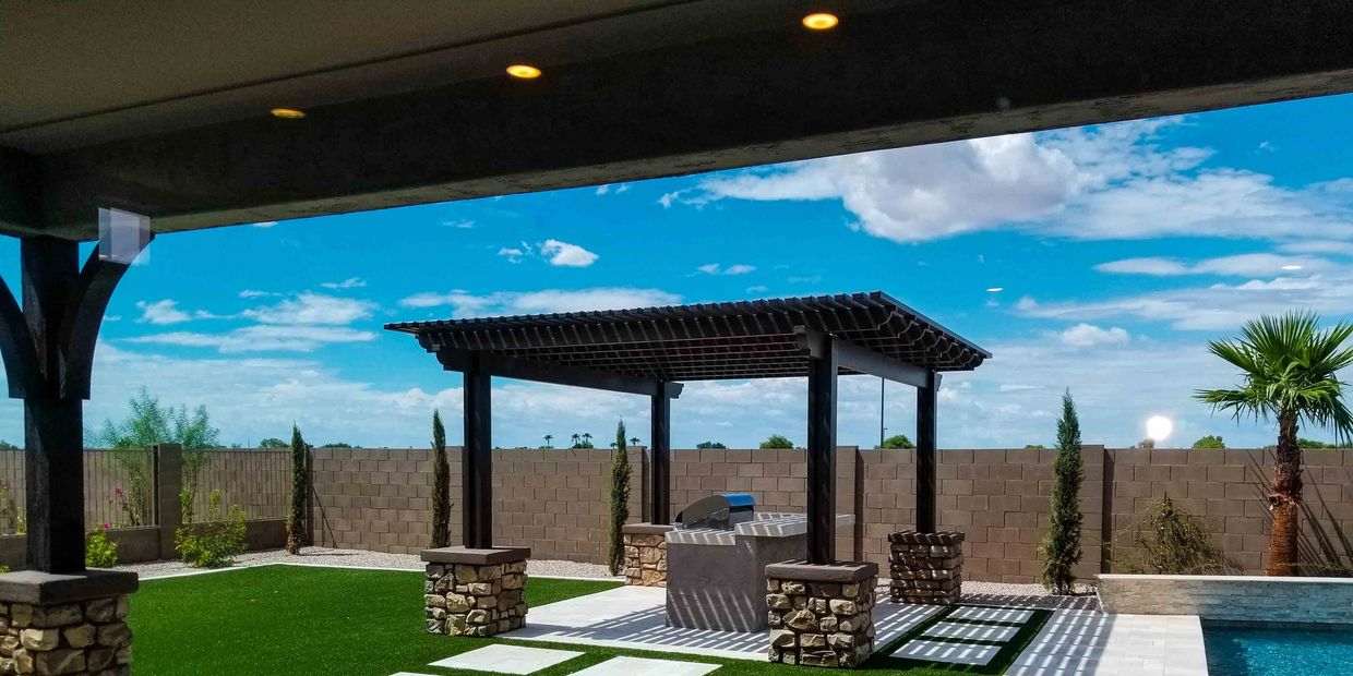 Outdoor patio with pergola and pool under a partly cloudy sky.