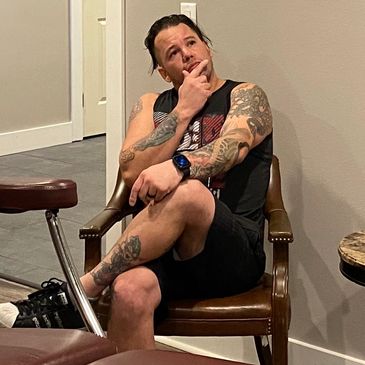 A man with tattoos sitting on a chair