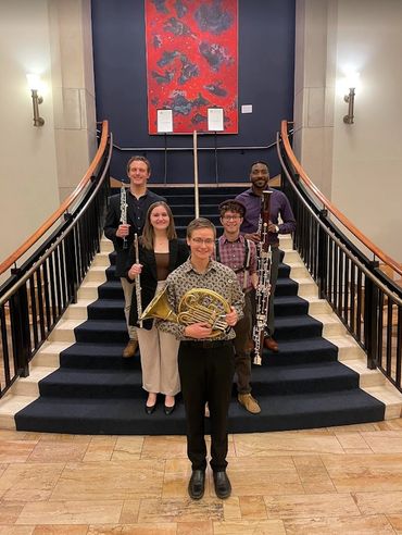 Five musicians stand together.