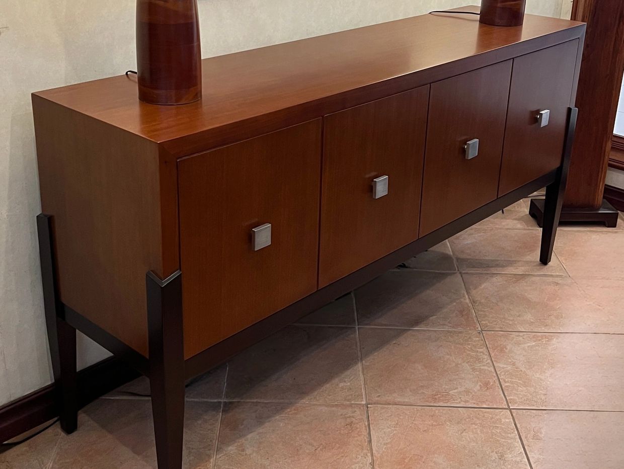 Modern wooden sideboard with four doors and metal handles on a tiled floor.