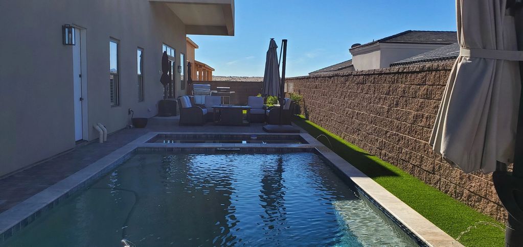 Modern backyard pool with seating area and walls.
