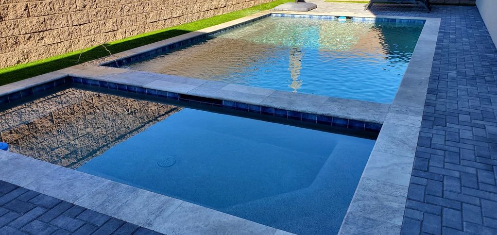 A backyard pool with clear blue water and a paved path.