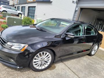 Black luxury sedan parked in front of a house.