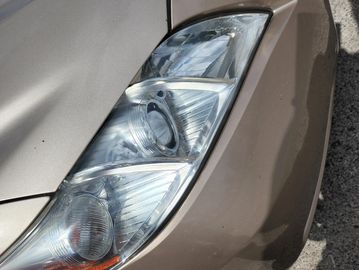 Close-up of a car's front headlight and hood.