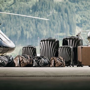 Luxury suitcases and duffel bags near a private jet.