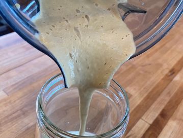 Pouring creamy batter into a glass jar.