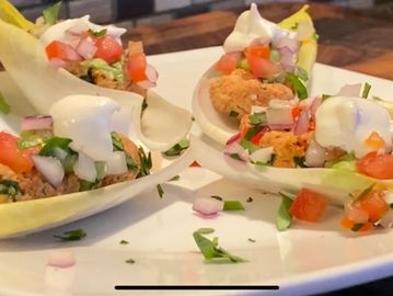 Appetizer served on lettuce leaves with toppings and sauce.
