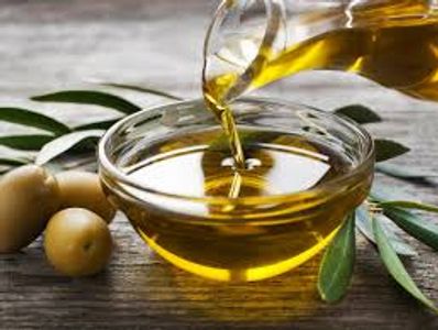 Olive oil being poured into a glass bowl.