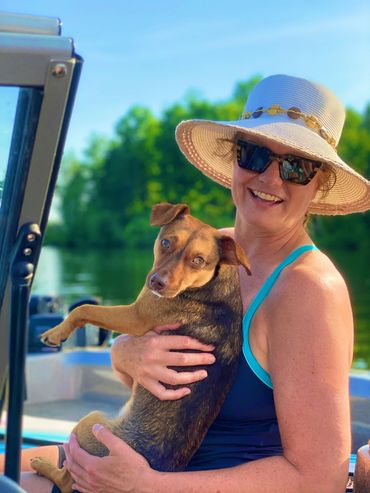 Alexi Venice hugging a dog in a boat 