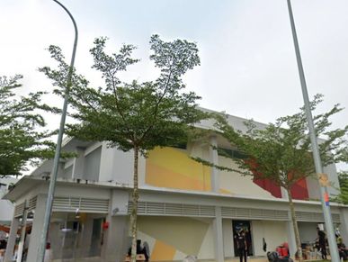 Two-story building with colorful geometric murals and trees in front.