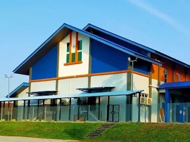 Modern building with blue roof and glass fencing on a grassy hill.