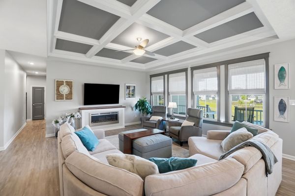 Bright living room with large windows, beige sectional sofa, and ceiling fan.