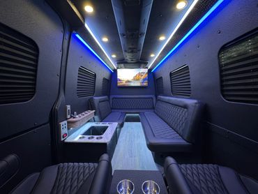 Luxurious party bus interior with blue LED lighting and leather seating.