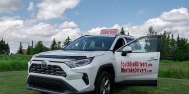 A white Rav 4 vehicle with an open door