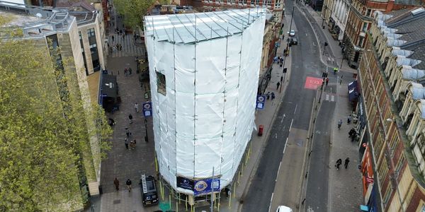 A large building covered in white scaffolding wrap in a city.