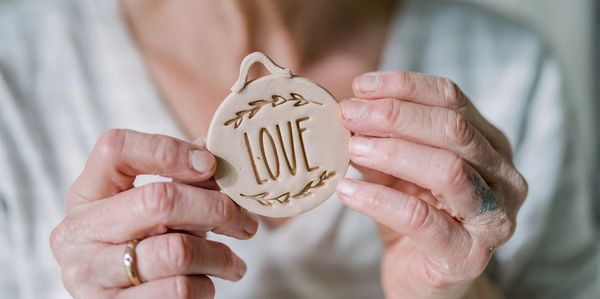 hands holding ceramic disc with the word love