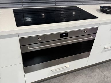 Modern kitchen with sleek black induction cooktop and stainless steel oven.