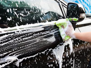hands hold sponge for cleaning and washing car at work of place