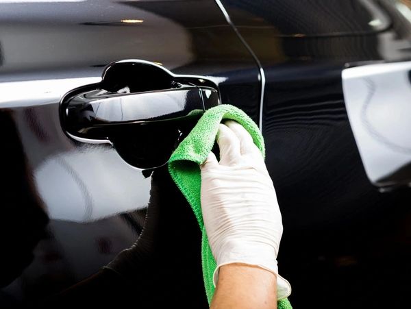 Worker cleaning black car