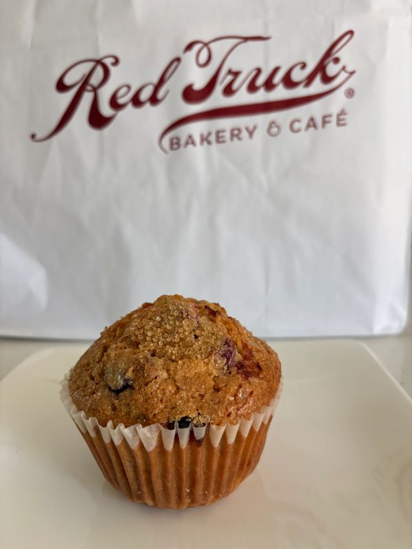 Blueberry muffin in front of Red Truck Bakery & Café bag.