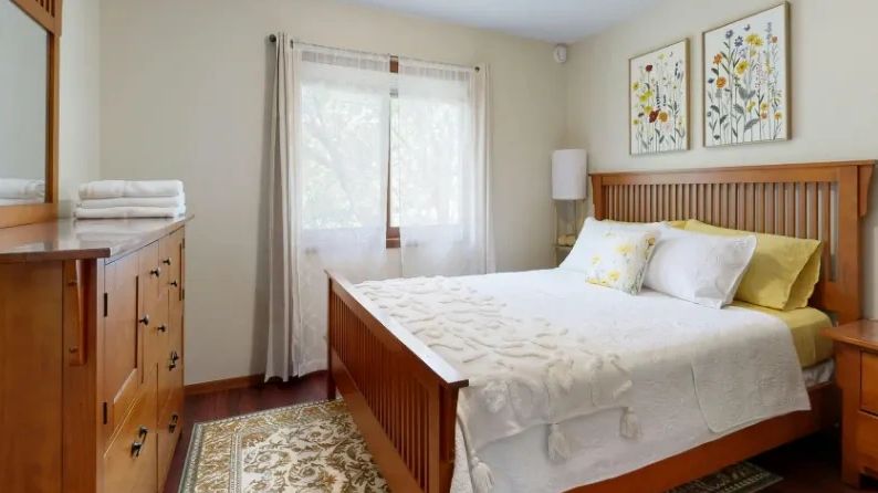 Cozy bedroom with wooden furniture and floral decor.